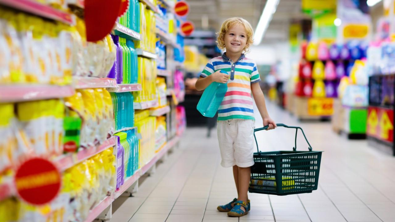 Child in supermarket buying fruit and juice. 儿童杂货店购物. Little boy with cart choosing fresh vegetables in local store.